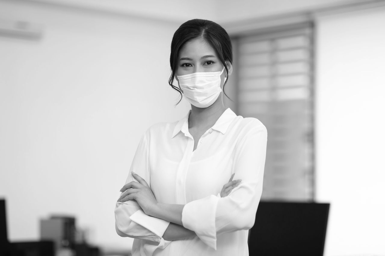 Asian business women leader wearing mask protection virus standing smile cross arm and confidence at Co-Working space Due Covid-19 Flu Pandemic,Health care and Business Startup Concept 
