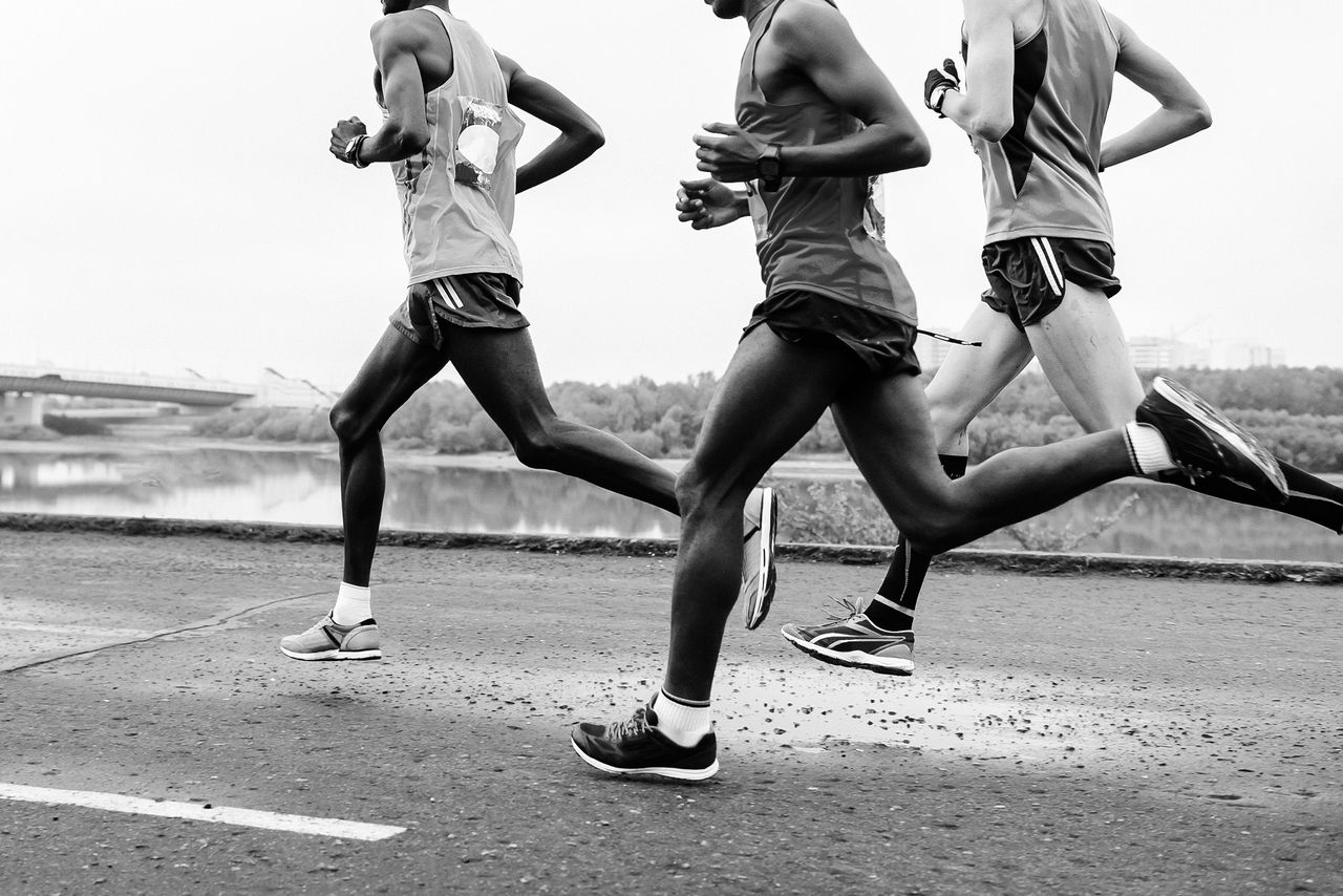 group runners leaders run along embankment of river black-and-white image