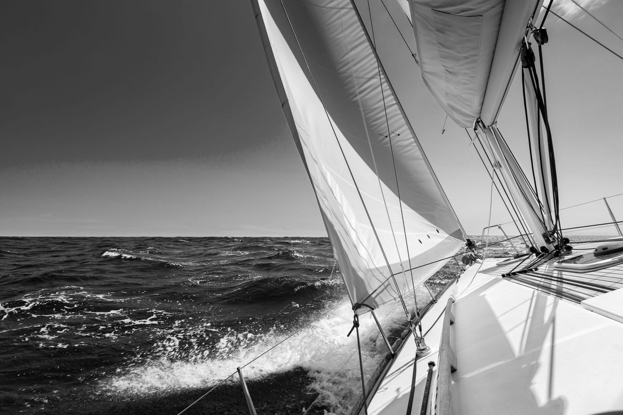 White sailing boat at open sea in sunshine