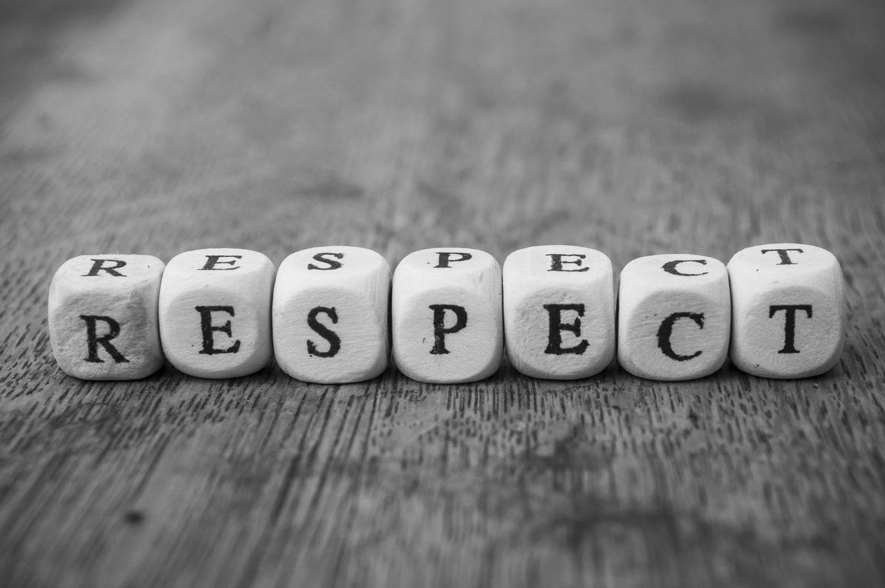 Closeup of word on wooden cube on wooden desk background concept - Respect 